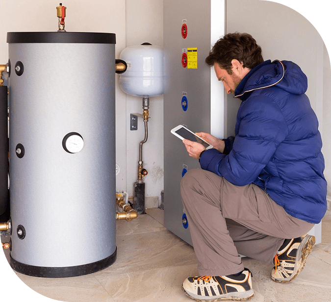 A man is using his tablet in front of an electric water heater.